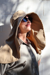 Woman wearing a beige Sun Safe hat that covers face and shoulders with sunglasses on.