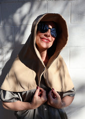 Woman wearing a beige Sun Safe hat that covers face and shoulders clipped in the middle with sunglasses on.